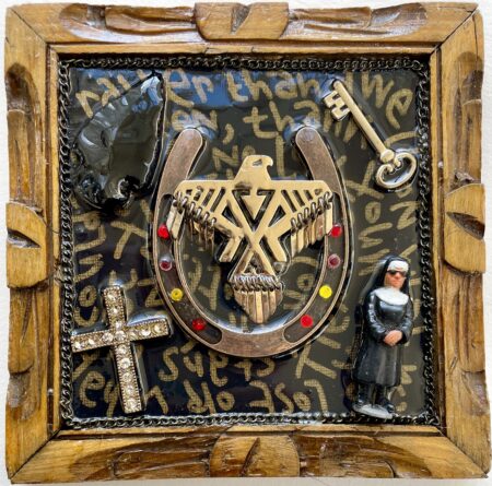 gold eagle with charm feathers, cool nun, skeleton key, bedazzled cross, flint; writing on backdrop framed by necklace chain carved wooden frame